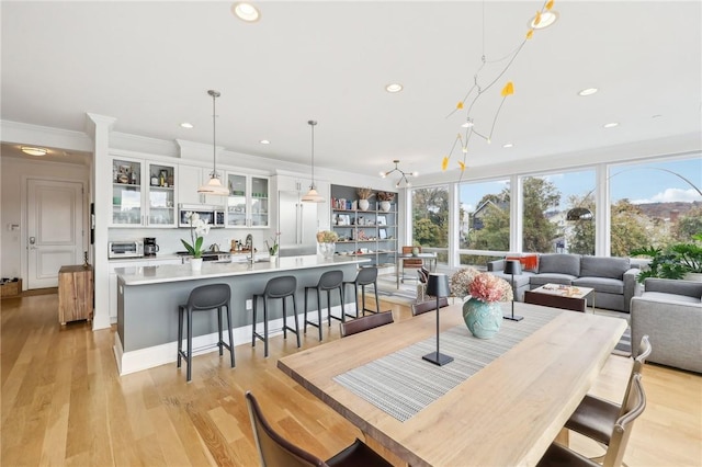 dining space featuring crown molding, light hardwood / wood-style flooring, and sink