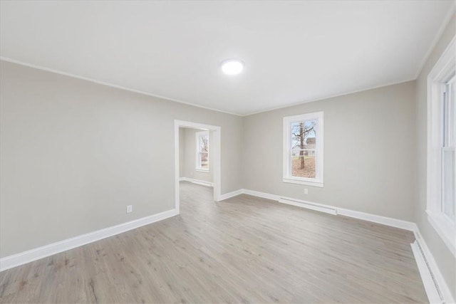 unfurnished room featuring light hardwood / wood-style floors, crown molding, and baseboard heating