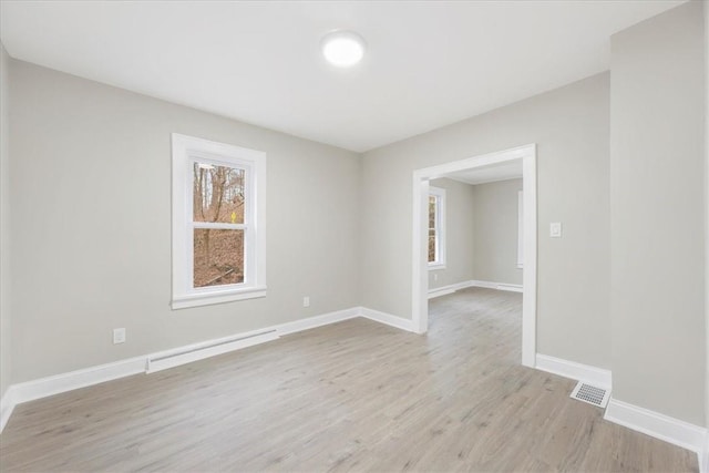 empty room with light wood-type flooring and baseboard heating