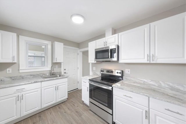 kitchen with appliances with stainless steel finishes, white cabinetry, and sink