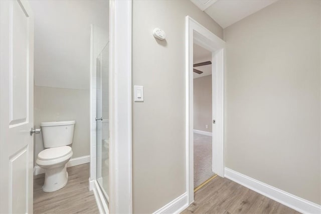 bathroom featuring ceiling fan, toilet, an enclosed shower, and hardwood / wood-style flooring