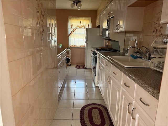 kitchen featuring appliances with stainless steel finishes, tasteful backsplash, sink, light tile patterned floors, and white cabinetry