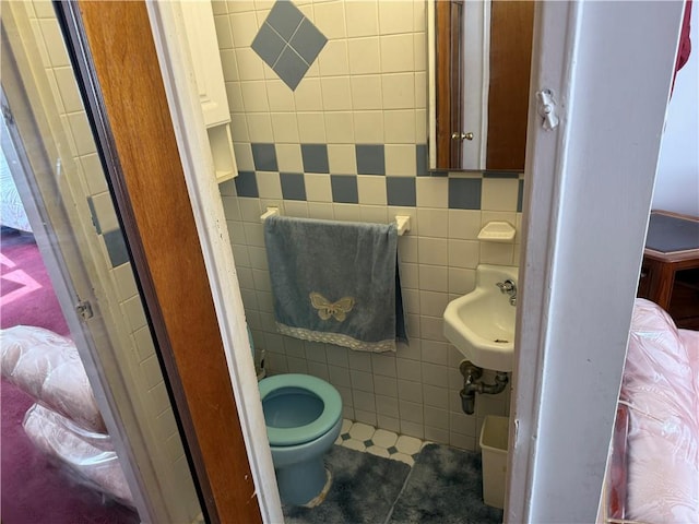 bathroom featuring tile patterned floors, sink, toilet, and tile walls