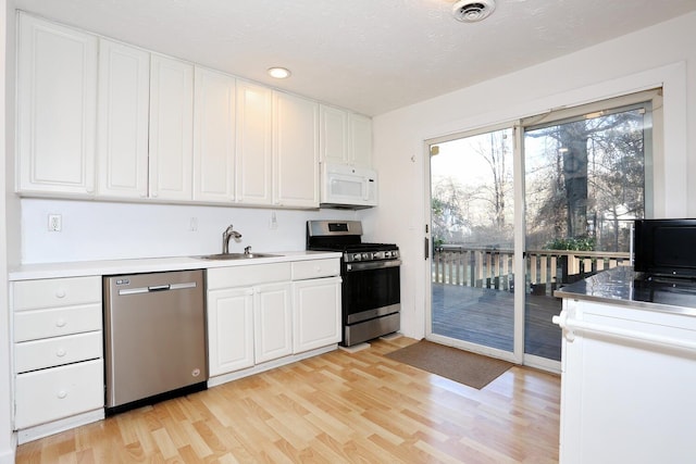 kitchen with sink, white cabinets, light wood-type flooring, and appliances with stainless steel finishes