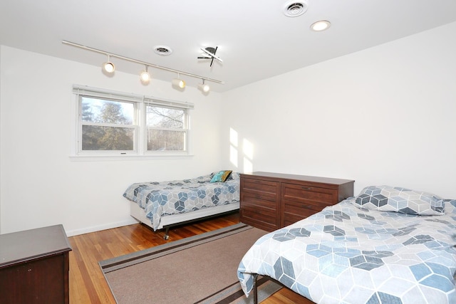 bedroom featuring hardwood / wood-style floors and rail lighting