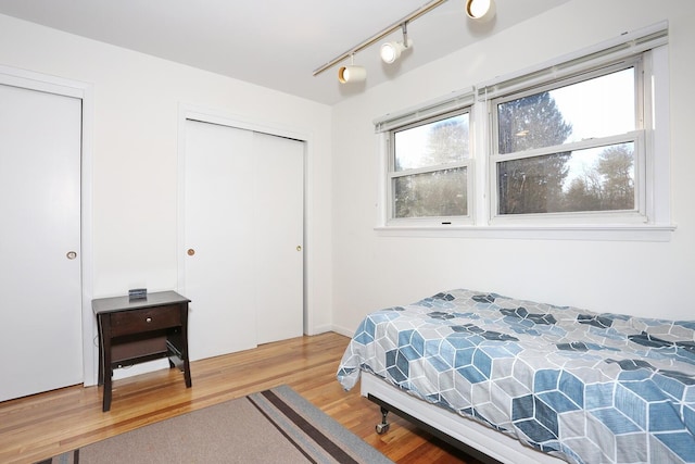 bedroom with wood-type flooring and track lighting