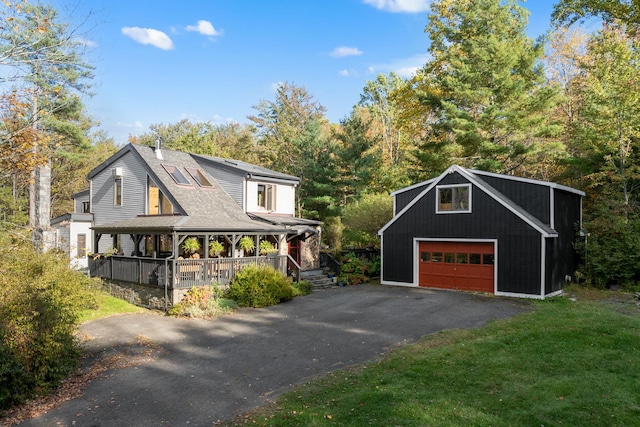 exterior space featuring an outbuilding, covered porch, a front yard, and a garage