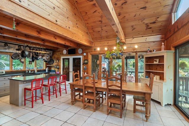 tiled dining room with vaulted ceiling with beams, wood walls, french doors, and wooden ceiling