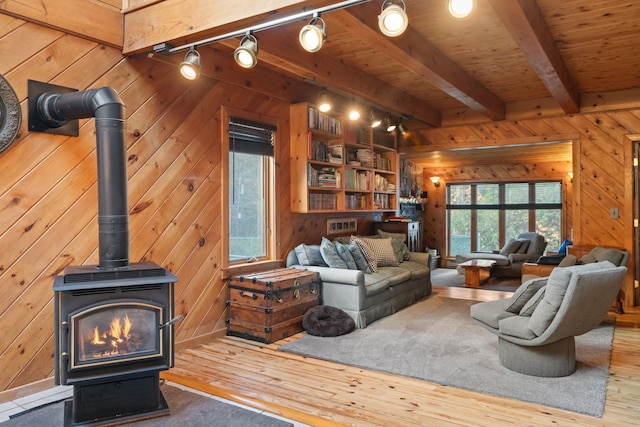 living room featuring track lighting, hardwood / wood-style flooring, a wood stove, and wooden walls