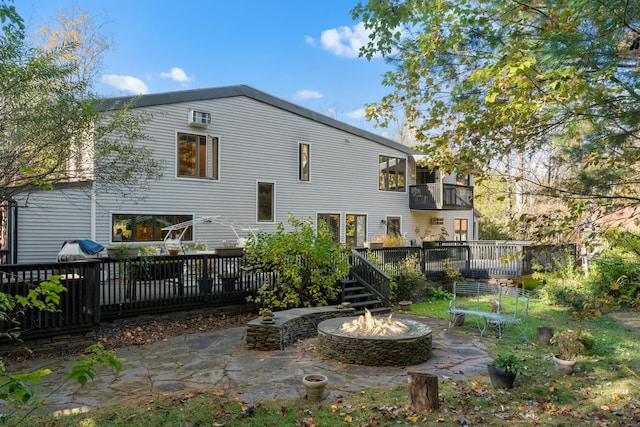 rear view of property featuring a fire pit, a deck, and a patio area