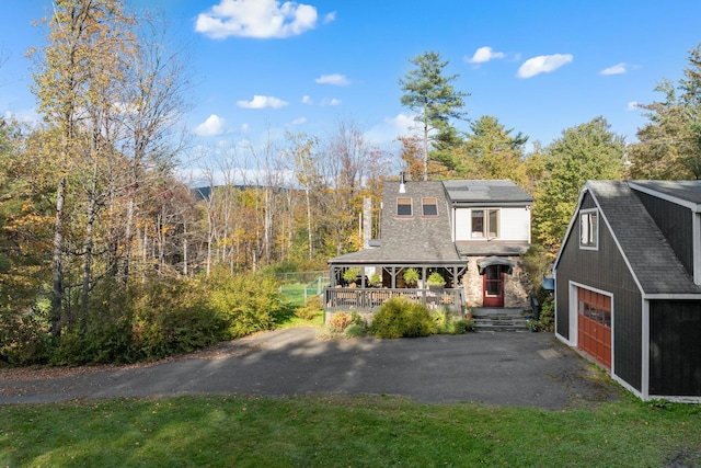 view of front of house featuring a porch, a garage, and an outbuilding