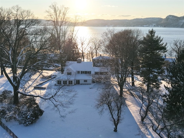 snowy aerial view featuring a water and mountain view