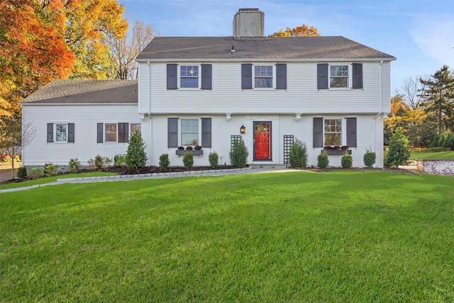 colonial inspired home featuring a chimney, a front lawn, and a shingled roof