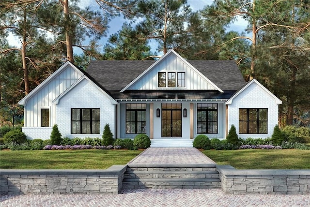 modern farmhouse with a shingled roof, a front yard, brick siding, and board and batten siding