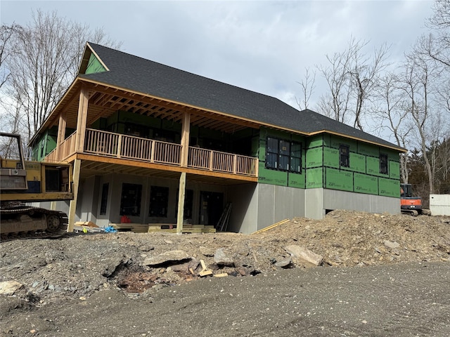 rear view of house featuring a shingled roof and a wooden deck