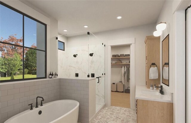 bathroom with recessed lighting, vanity, tile walls, a freestanding bath, and a marble finish shower