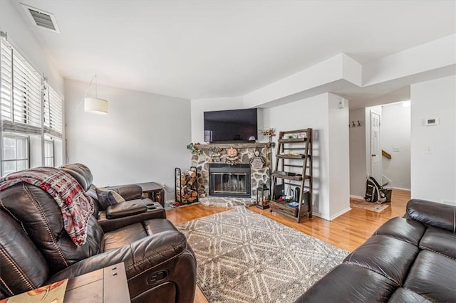 living room featuring a stone fireplace and wood-type flooring