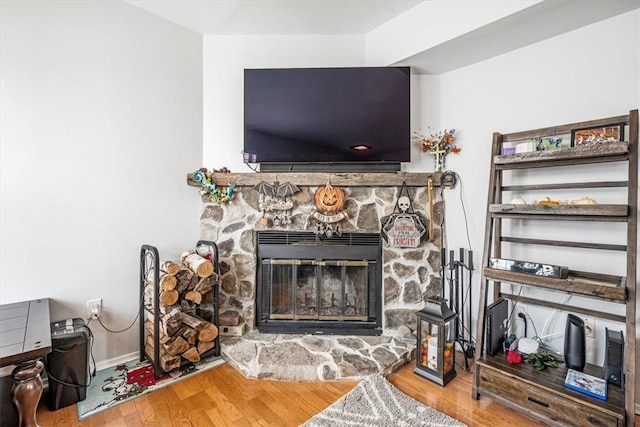 interior details with wood-type flooring and a stone fireplace