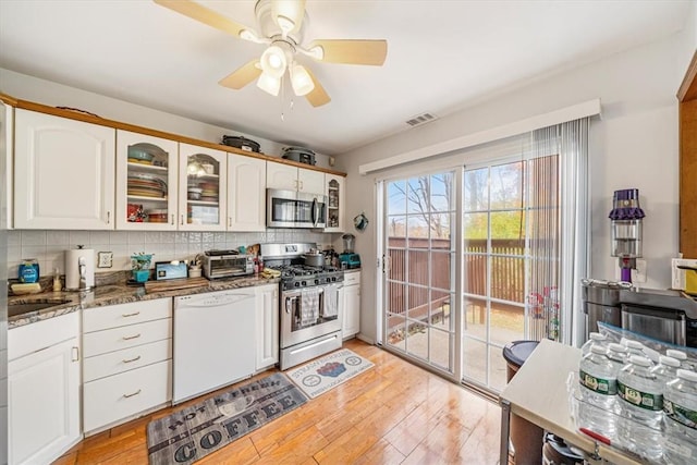 kitchen with dark stone countertops, light hardwood / wood-style flooring, white cabinets, and stainless steel appliances