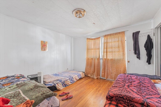 bedroom featuring hardwood / wood-style floors, a textured ceiling, and wooden walls