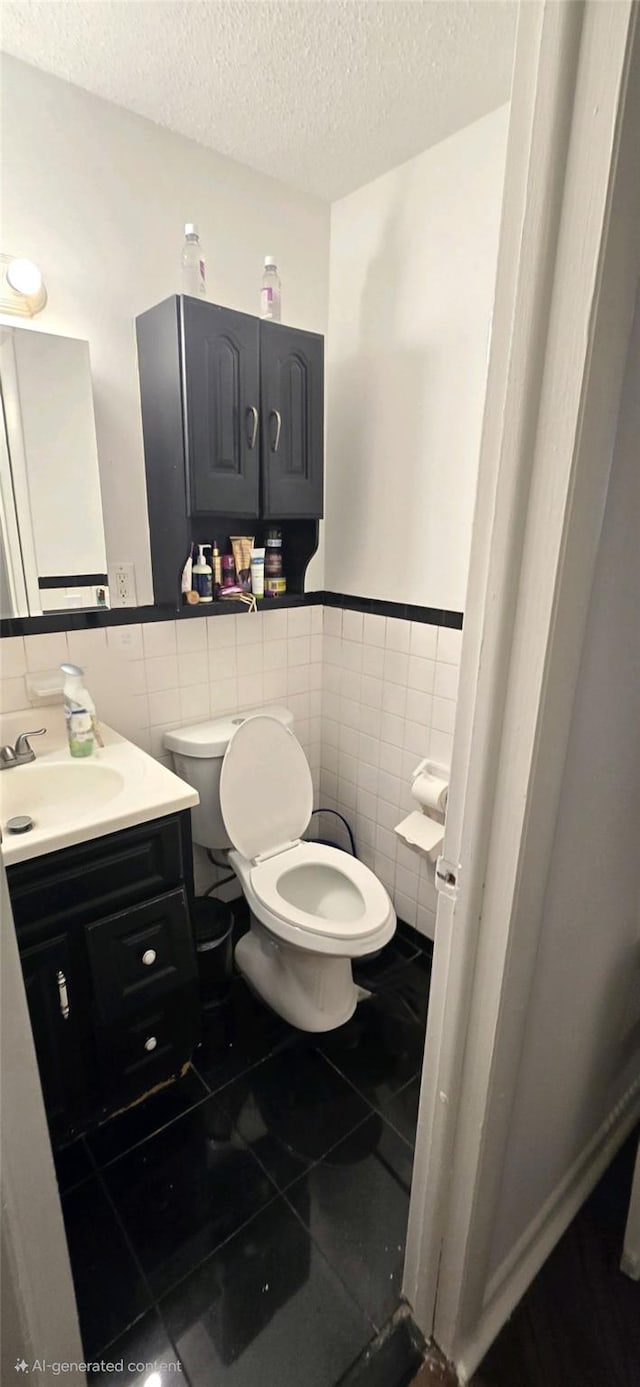 bathroom with vanity, tile walls, a textured ceiling, and toilet