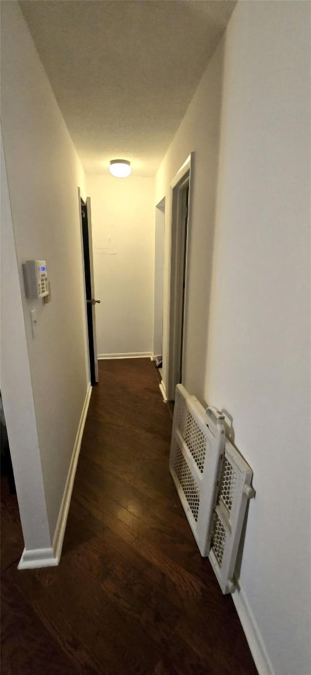 hallway featuring dark hardwood / wood-style flooring and a textured ceiling