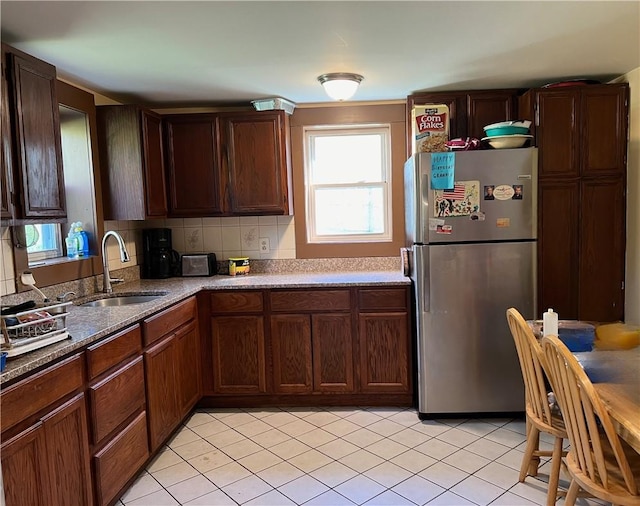 kitchen featuring decorative backsplash, stainless steel fridge, light tile patterned floors, and sink