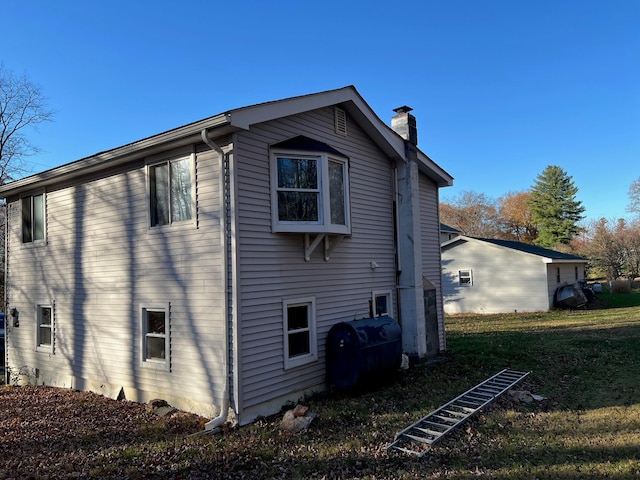 view of property exterior with a lawn, a chimney, and heating fuel