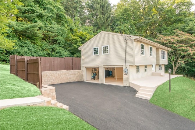 view of front of property with an attached garage, fence, driveway, and a front lawn