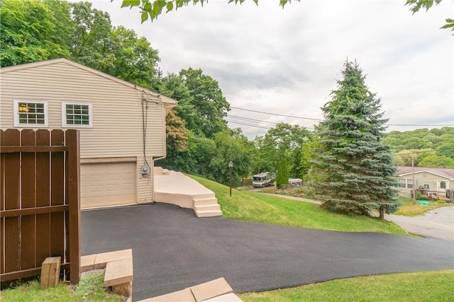 view of side of property featuring a garage and aphalt driveway