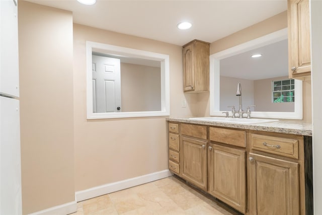 kitchen featuring light stone countertops, baseboards, a sink, and recessed lighting