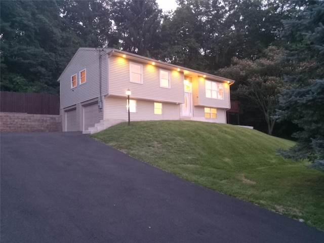 split foyer home with driveway, an attached garage, and a front yard