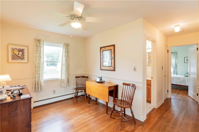 sitting room featuring wood-type flooring, baseboard heating, and ceiling fan