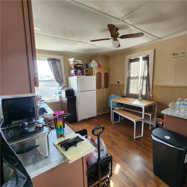 kitchen with hardwood / wood-style floors, wood walls, white refrigerator, crown molding, and ceiling fan