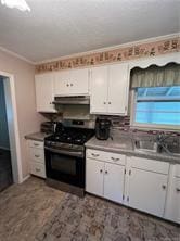 kitchen with white cabinetry, stainless steel electric range oven, sink, and crown molding