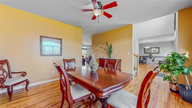 dining space with ceiling fan with notable chandelier and light wood-type flooring