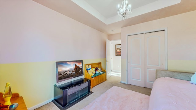 carpeted bedroom with a chandelier, a tray ceiling, and a closet