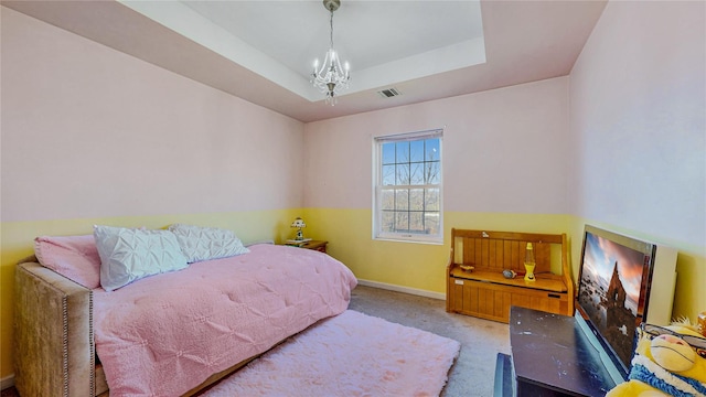 carpeted bedroom with a tray ceiling and a notable chandelier