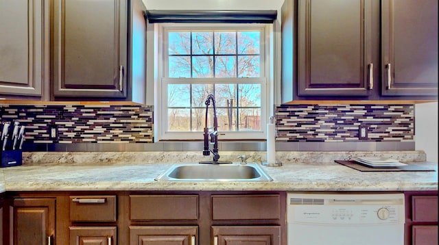 kitchen featuring decorative backsplash, white dishwasher, and sink