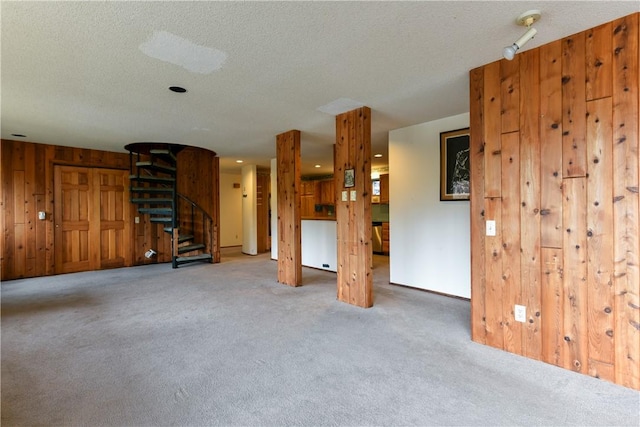 unfurnished living room with wood walls, carpet, and a textured ceiling