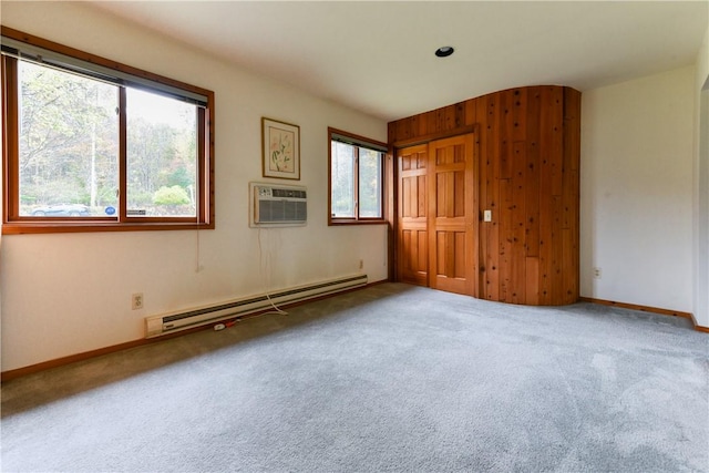 unfurnished room with carpet flooring, an AC wall unit, a wealth of natural light, and a baseboard radiator