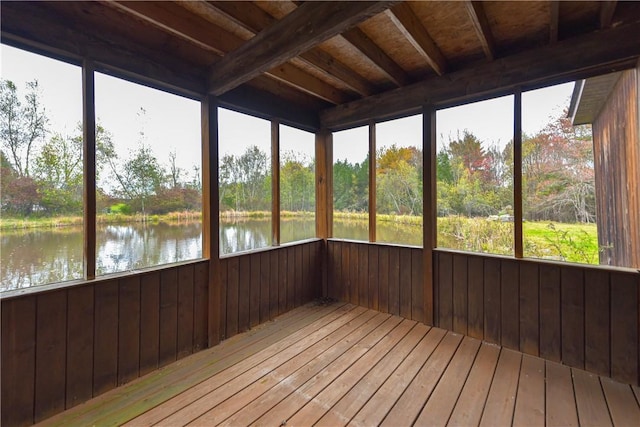 unfurnished sunroom featuring beam ceiling and a water view