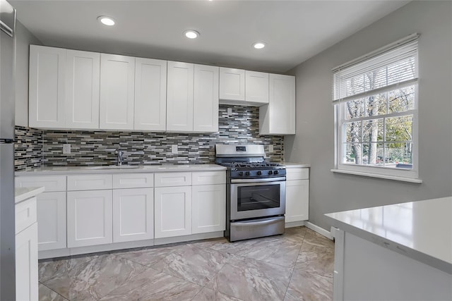 kitchen with white cabinets, gas range, tasteful backsplash, and sink