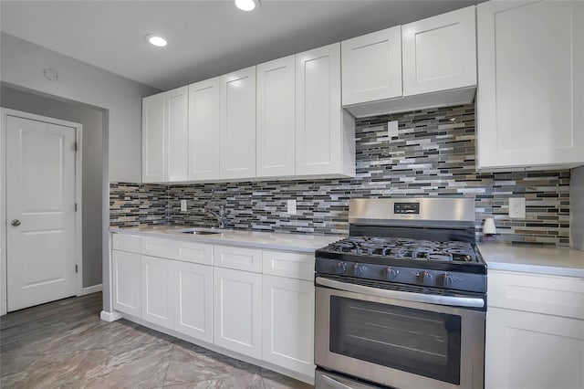 kitchen with white cabinets, backsplash, stainless steel gas range oven, and sink