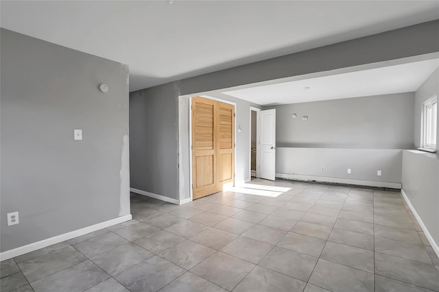 unfurnished room with light tile patterned floors and a baseboard radiator