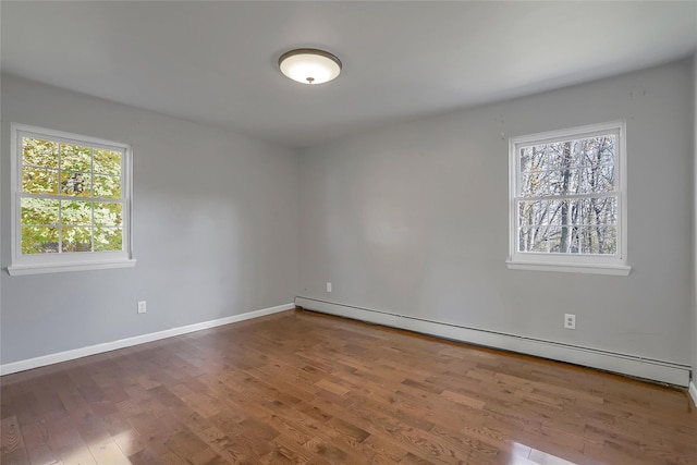 empty room with a healthy amount of sunlight, wood-type flooring, and a baseboard radiator