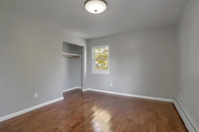 unfurnished bedroom with a baseboard radiator, a closet, and dark wood-type flooring