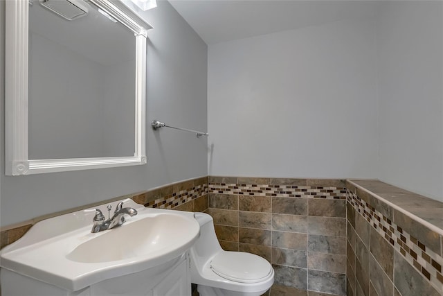 bathroom with vanity, tile walls, and toilet