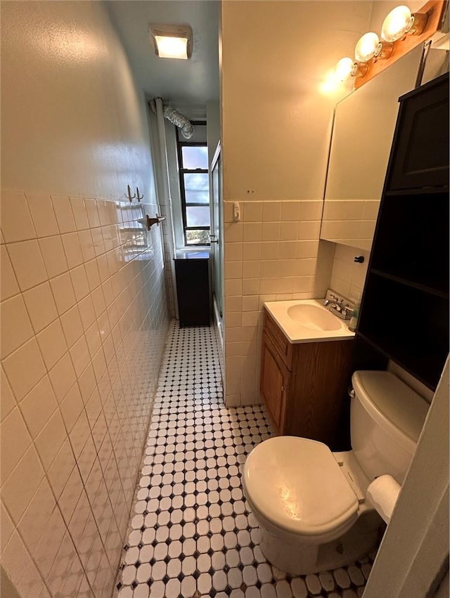 bathroom featuring vanity, toilet, tile walls, and walk in shower