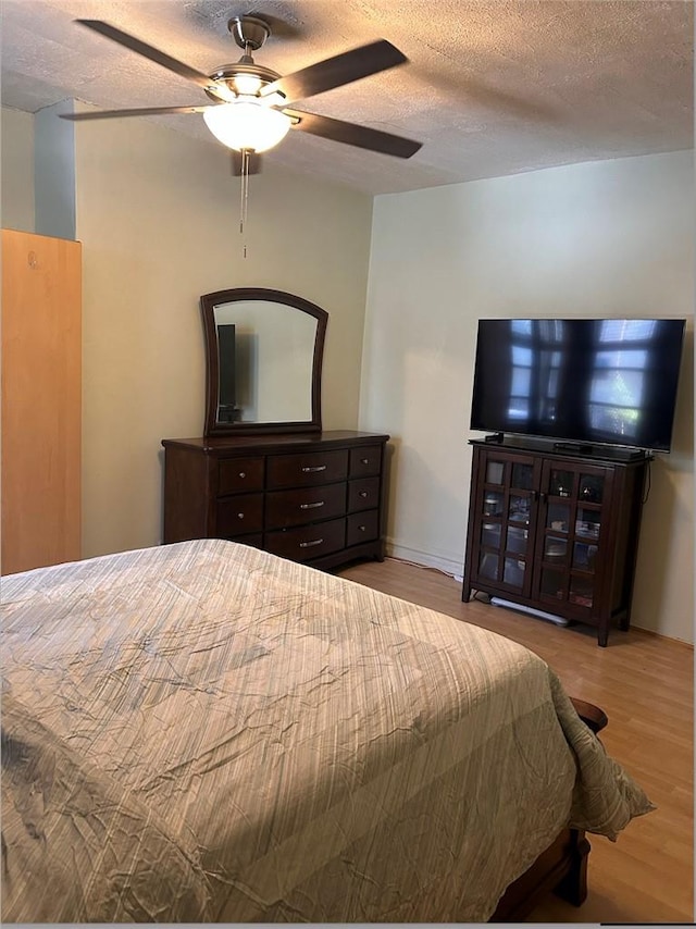 bedroom featuring ceiling fan, a textured ceiling, and light hardwood / wood-style flooring